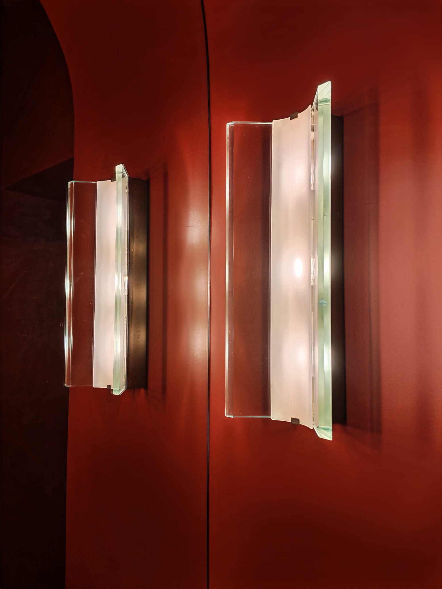 Pair of glass wall sconces on a red wall